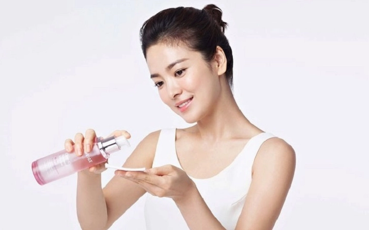 Cô gái thoa nước hoa hồng lên mặt bằng tay