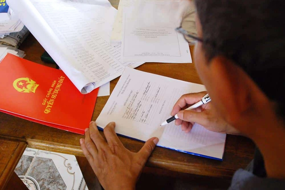 Hình ảnh bàn tay cầm bút ký giấy tờ liên quan đến thuế