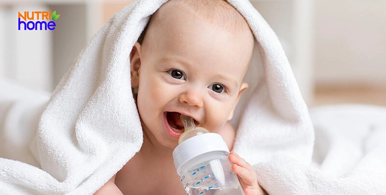 Bé 6 tháng tuổi đang uống nước lọc từ bình